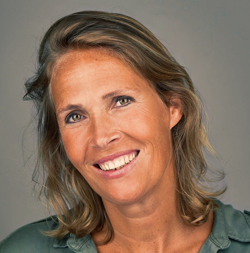 Smiling woman with light brown hair; wearing green shirt.
