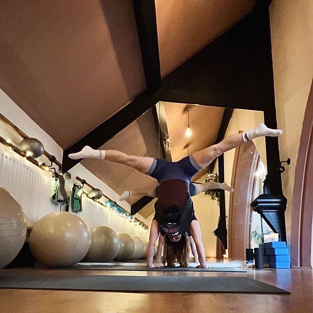 A woman is doing a handstand in a gym
