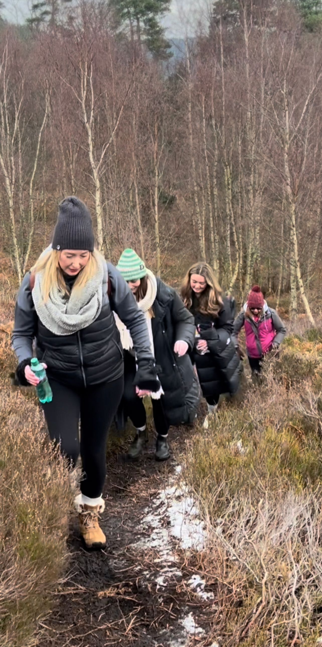 A group of people are walking down a path in the woods.