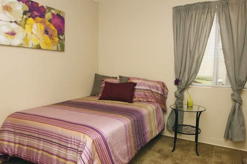 Bedroom with a bed, striped purple bedding, and a small round side table by the window.