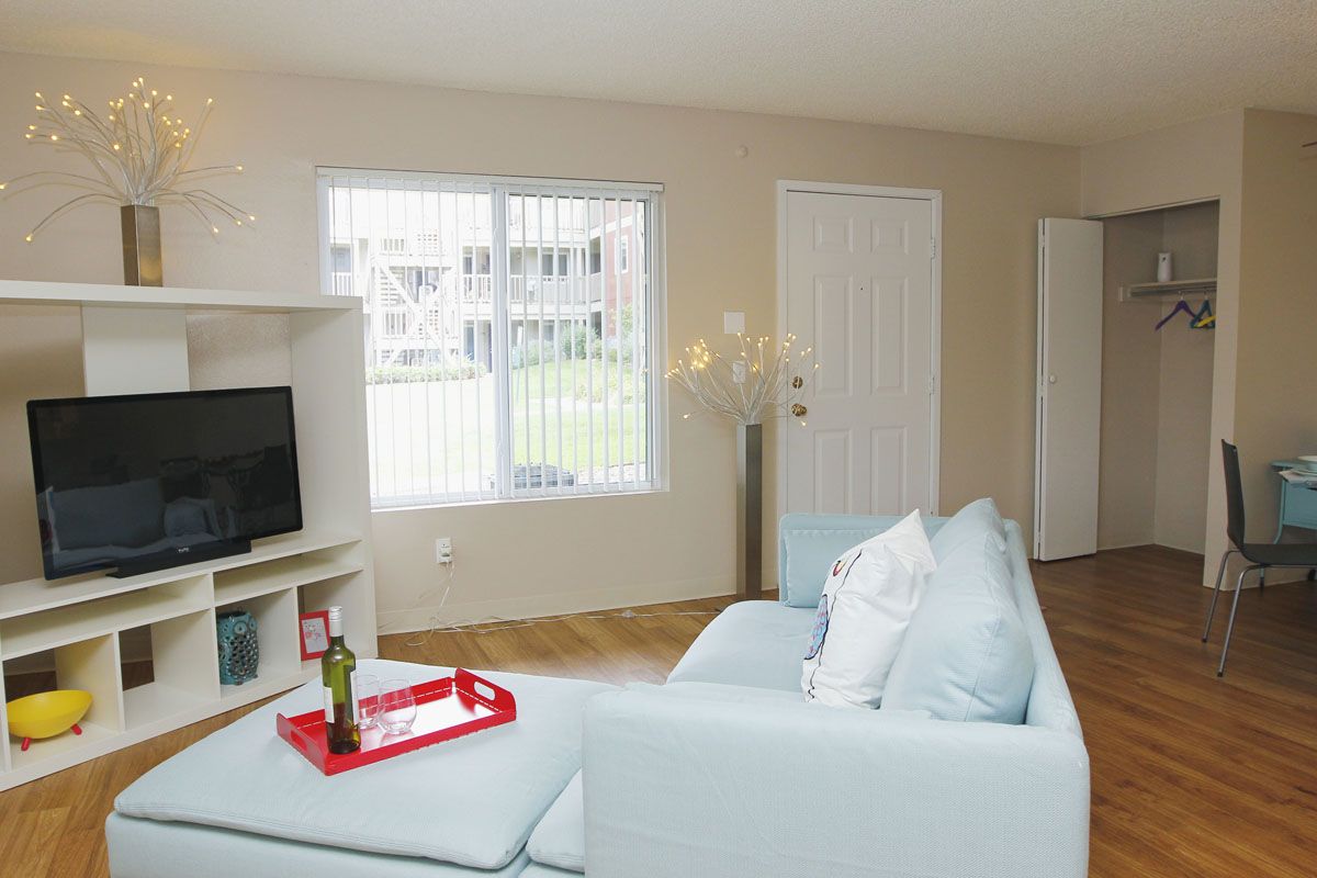 Living room in apartment with pale blue sofa, TV stand, and large window.