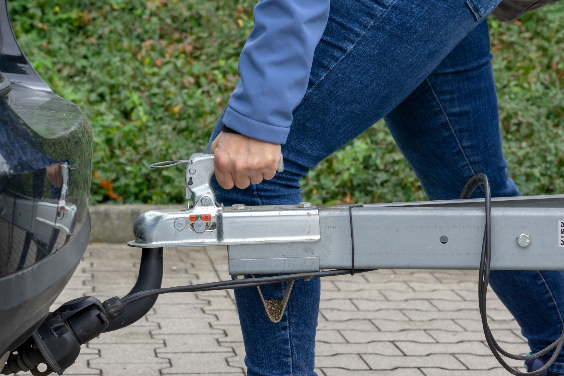 A woman is pulling a trailer attached to a car.