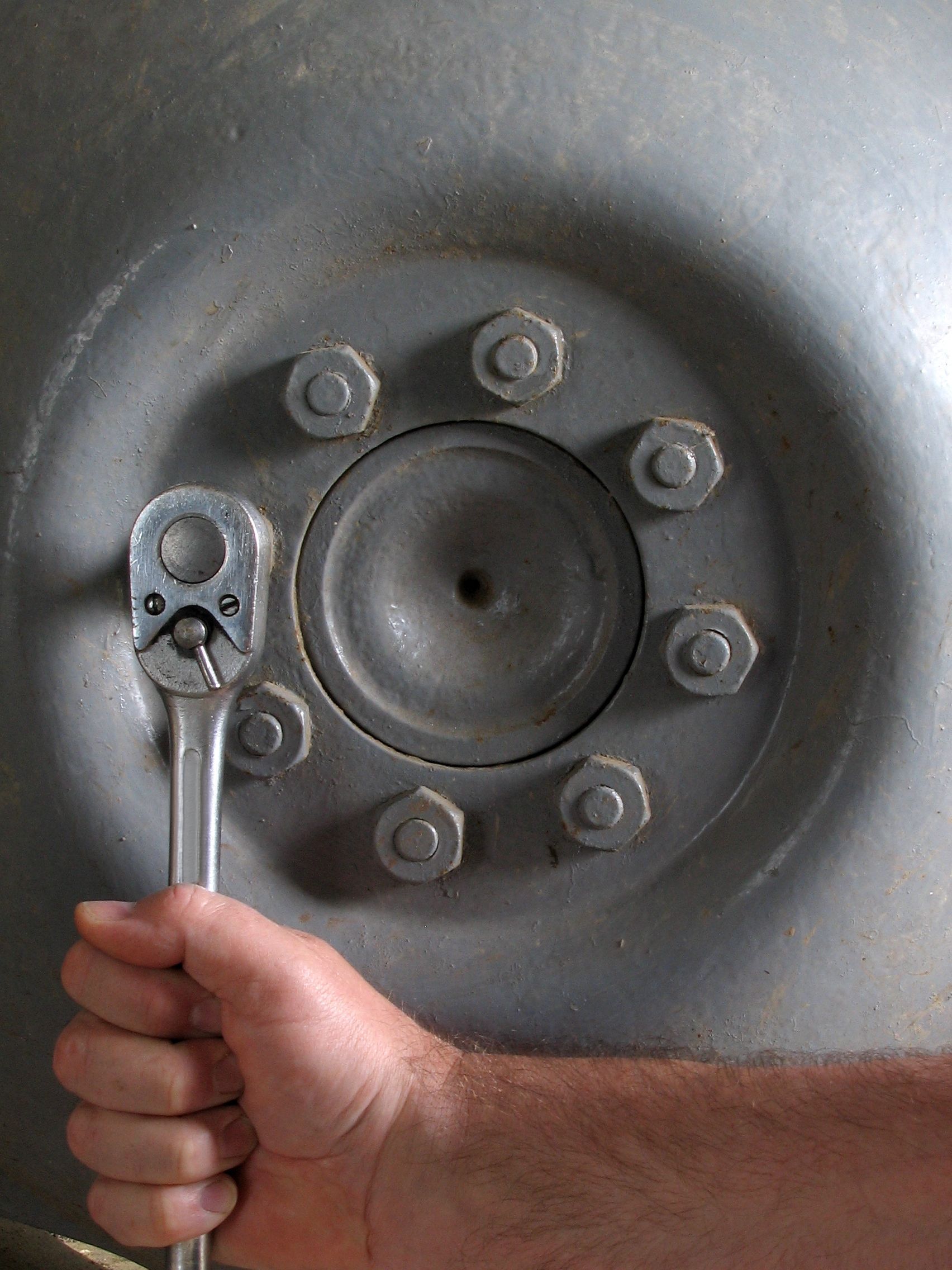 A person is holding a wrench in front of a wheel