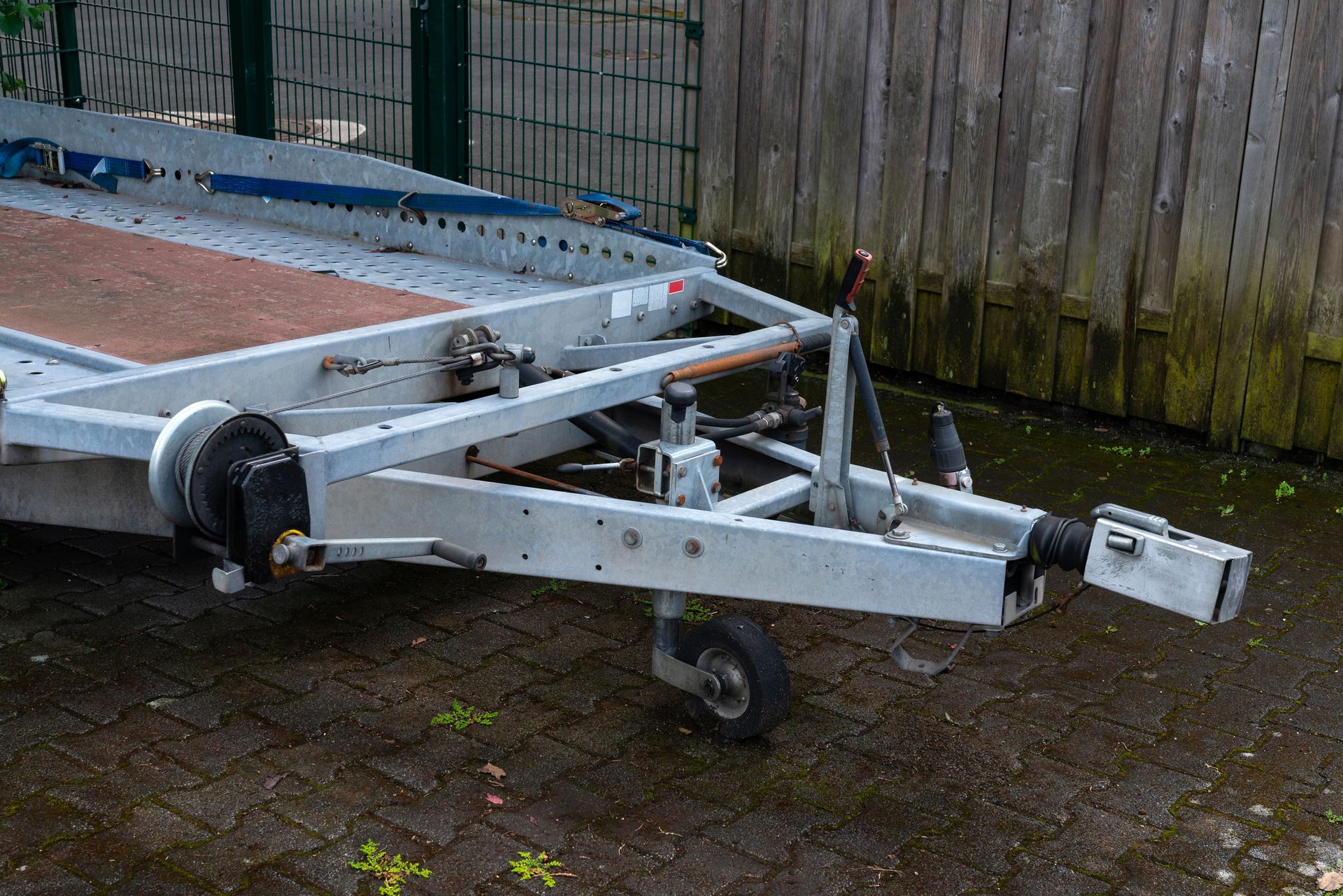 A trailer is parked in front of a wooden fence.