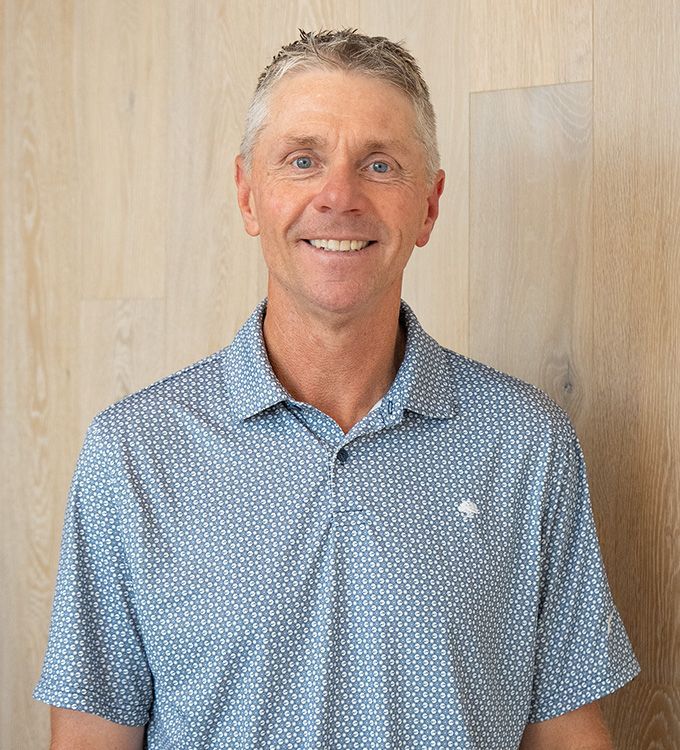 Smiling man in a blue striped polo shirt against a dark background