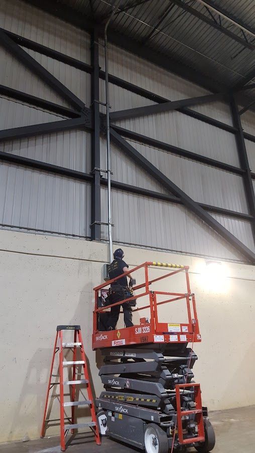 Un homme se tient debout sur un élévateur à ciseaux dans un entrepôt.