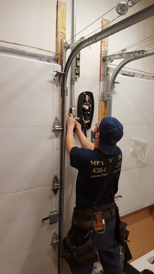 Un homme travaille sur une porte de garage dans un garage.