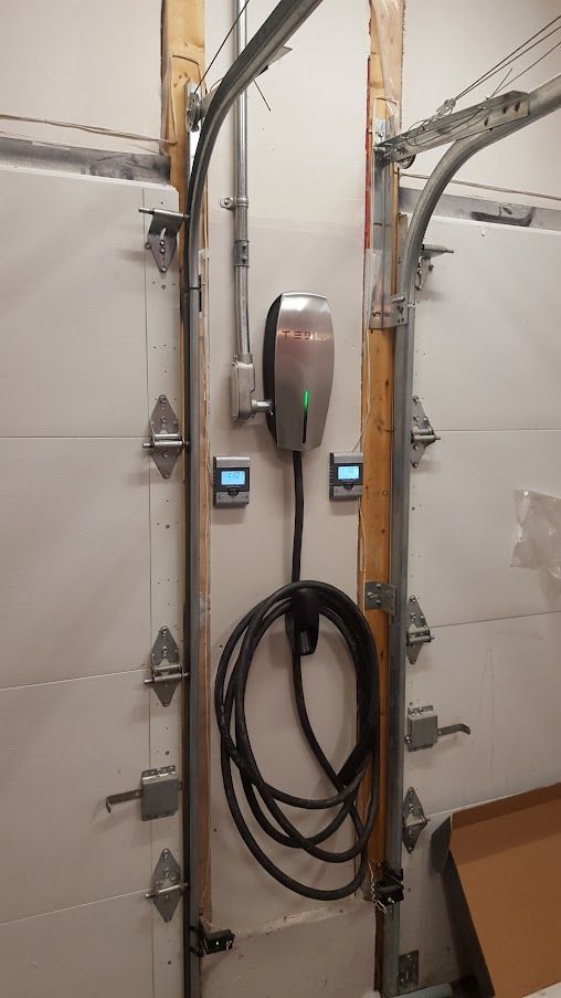 Une borne de recharge Tesla est fixée sur le côté d'une porte de garage.