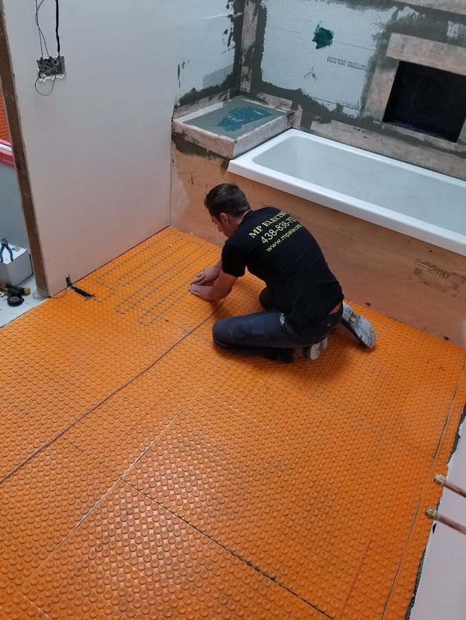 Un homme est agenouillé sur le sol dans une salle de bain à côté d'une baignoire.