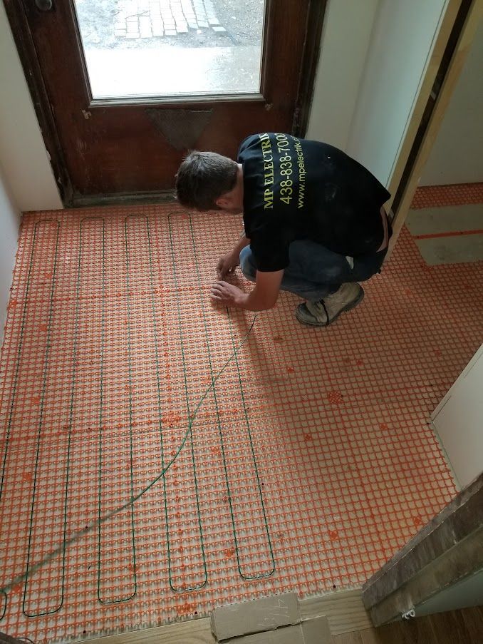 Un homme est agenouillé sur un sol carrelé dans un couloir.