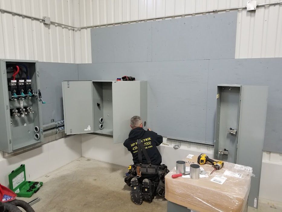 Un homme travaille sur un boîtier électrique dans une pièce.