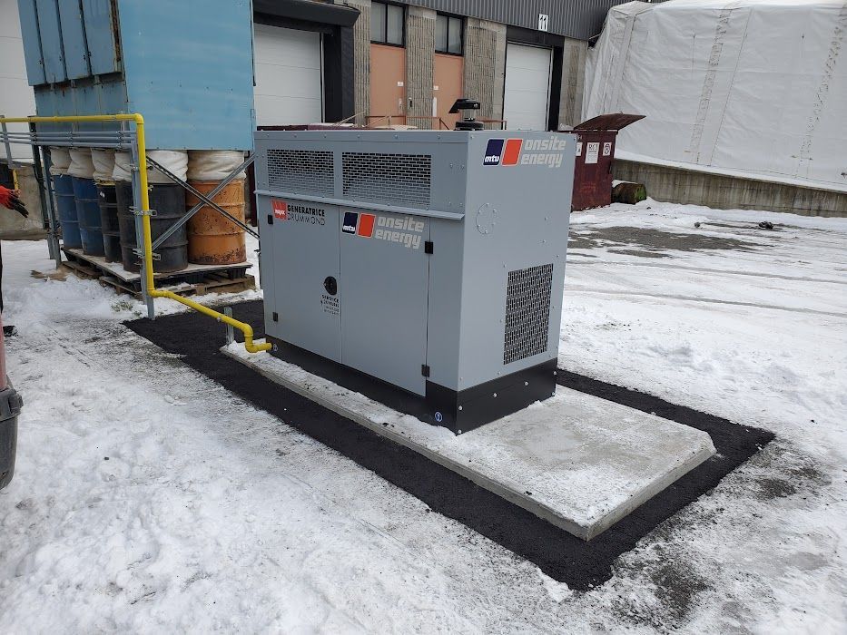 Un générateur est assis dans la neige devant un bâtiment.