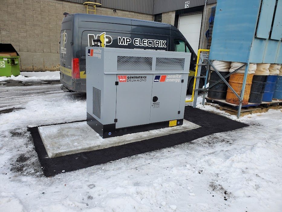 Un générateur est assis dans la neige à côté d'une camionnette.