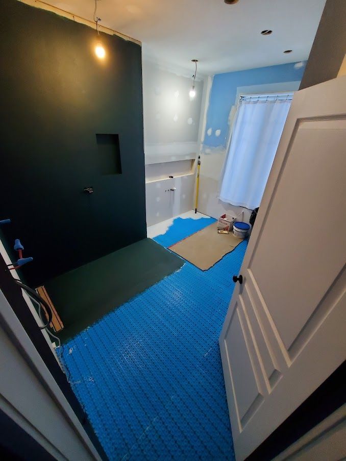 Une salle de bain en construction avec un tapis bleu au sol.