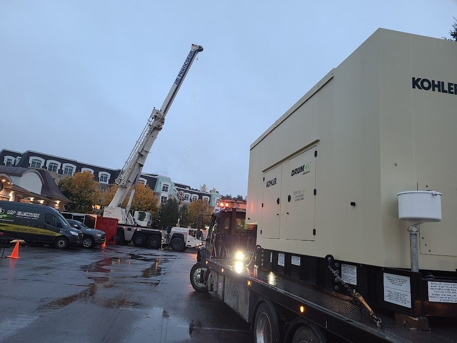 Un gros générateur Kohler est en train d'être chargé sur un camion.
