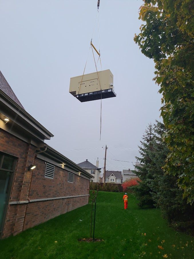 Un gros équipement est soulevé dans les airs par une grue.