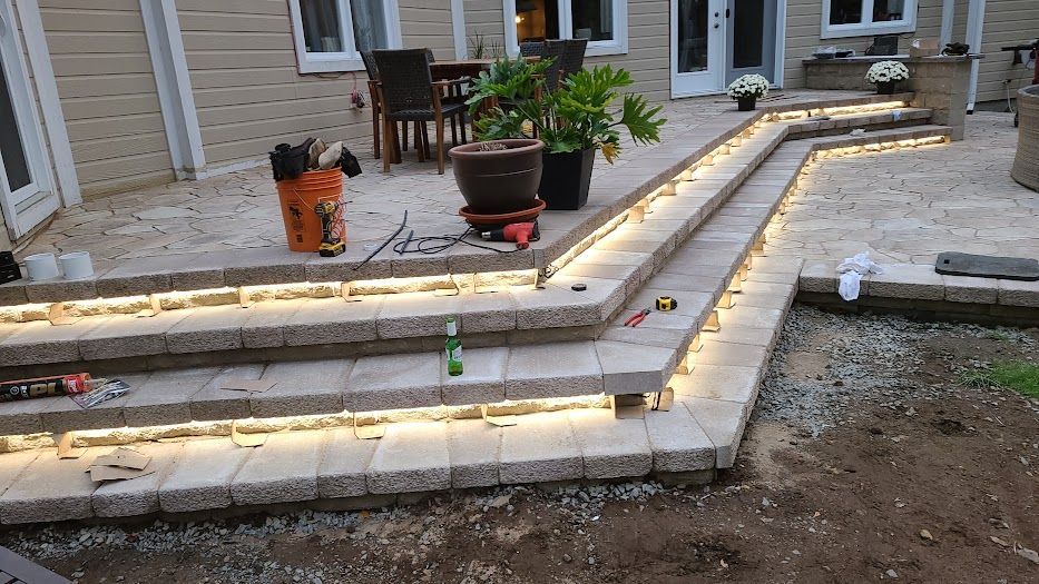 Un patio avec des escaliers et des lumières est en cours de construction.