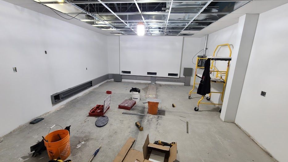 Une pièce vide avec un tableau blanc sur le mur et des outils sur le sol.