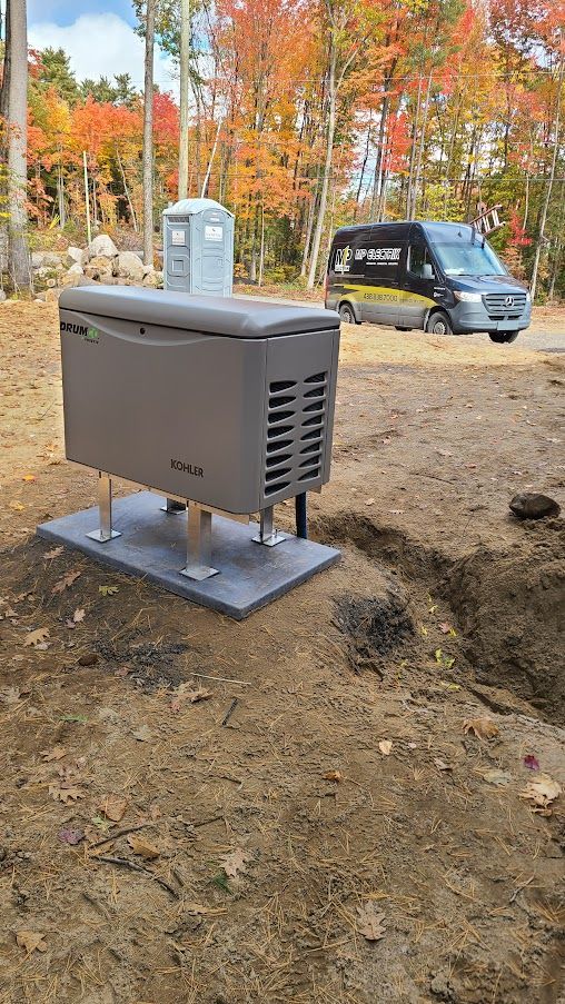 Un générateur est assis au milieu d'un champ de terre à côté d'une camionnette.