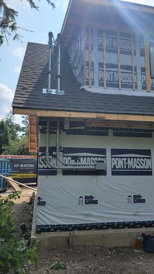 Une maison est en construction avec un toit noir et un mur blanc.