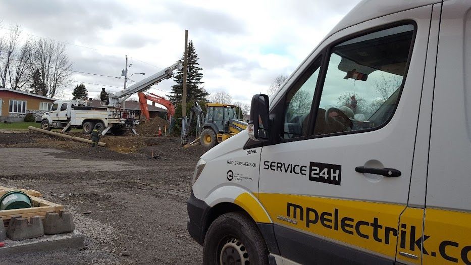 Une camionnette blanche et jaune est garée devant un chantier de construction.