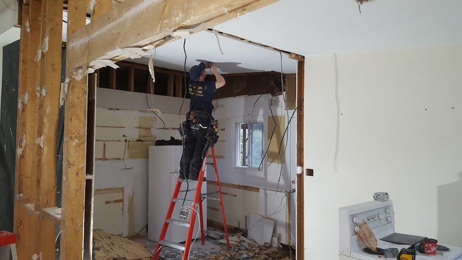 Un homme se tient debout sur une échelle dans une pièce.
