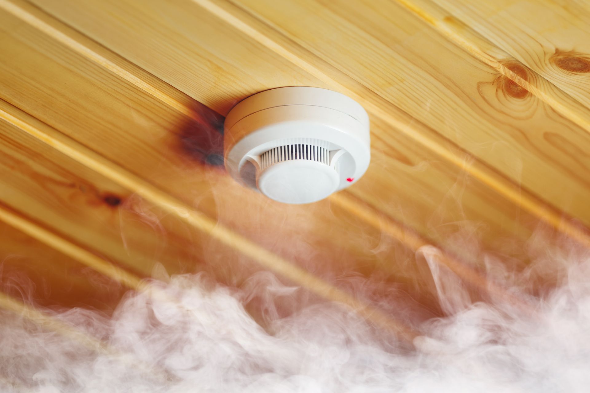 A Smoke Detector On A Wooden Ceiling With Smoke Coming Out Of It — Test Right Services in Kirwan, QLD