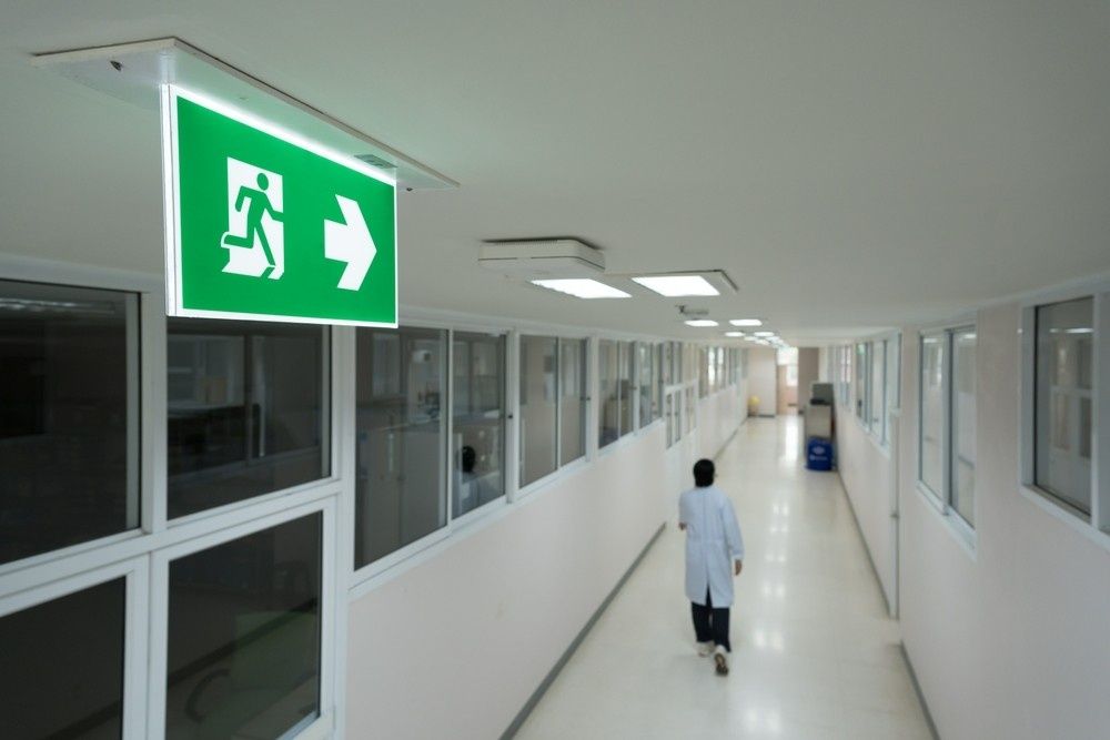 Green exit sign above a hallway, person walking toward the exit — Test Right Services in Kirwan, QLD