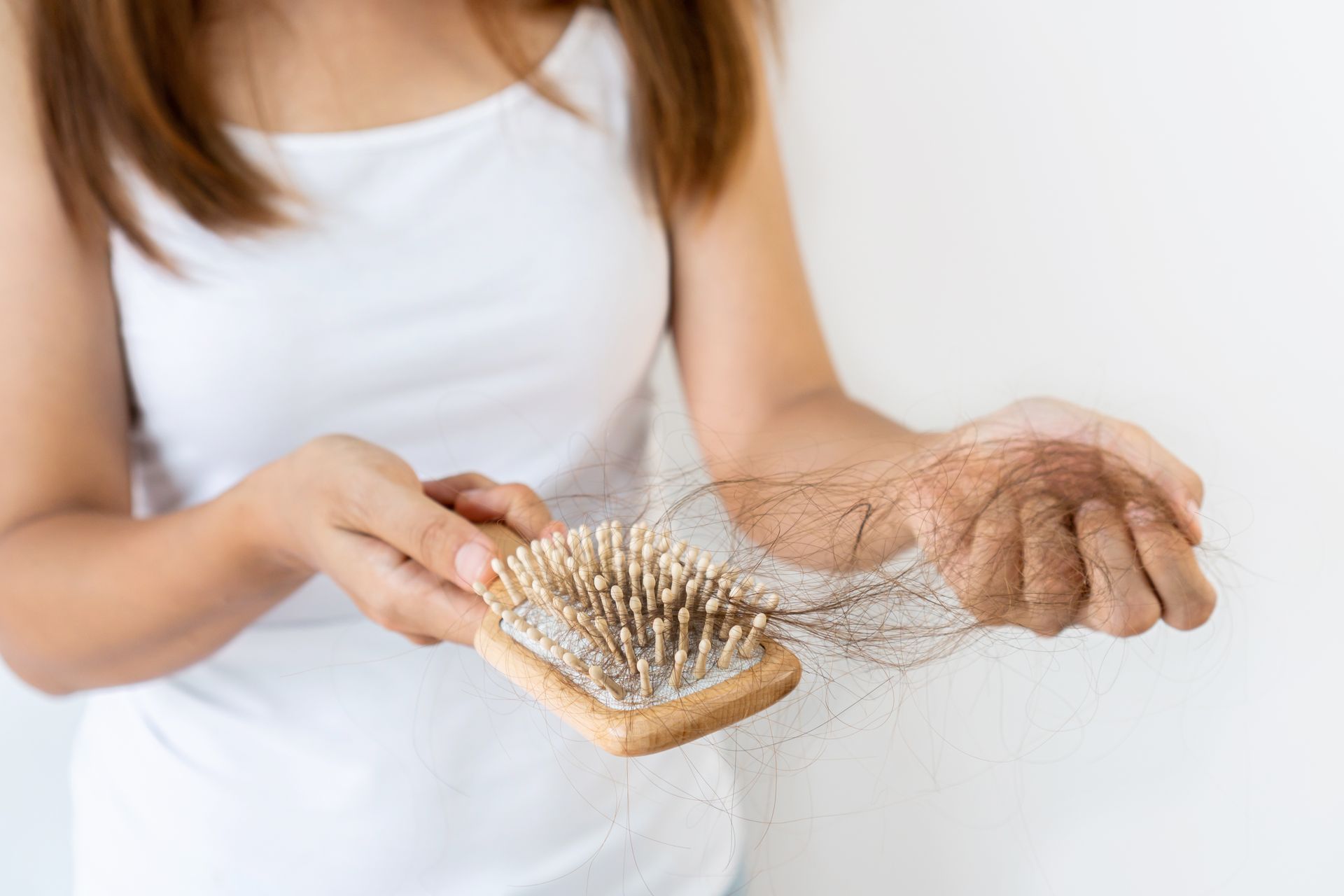 A woman is taking the hair off a hairbrush.