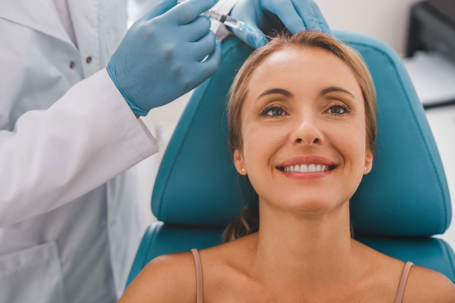 A patient is getting a head injection in a clinic, by a doctor, for women's hair loss treatment.