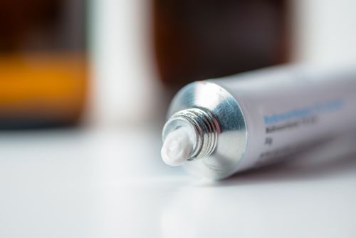 A tube of hydrocortisone cream on a white surface. A tube of hydrocortisone cream on a white surface.