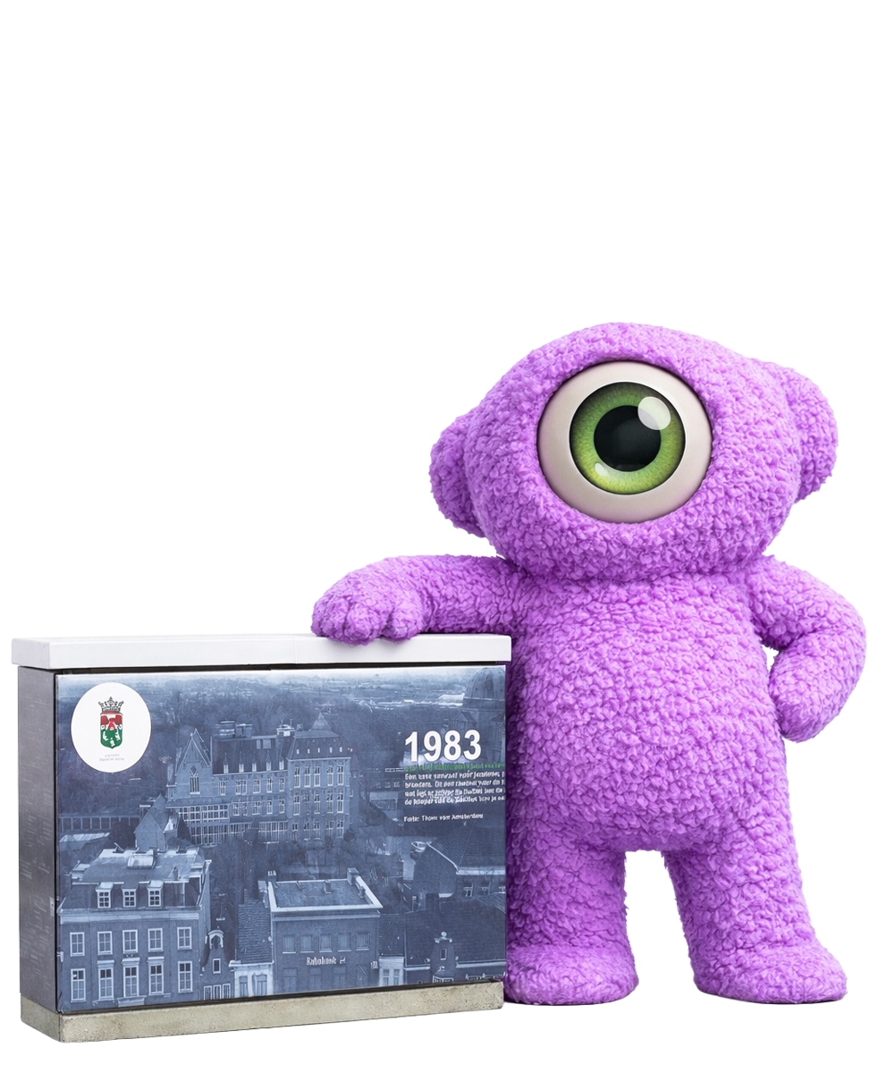 Een paars, eenogig pluche wezentje leunt tegen een doos met daarop 