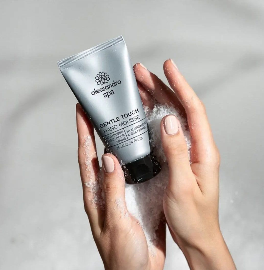 Mani che tengono in mano un tubetto grigio di 