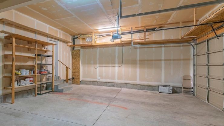 Empty garage interior with shelving, concrete floor, and closed garage door.