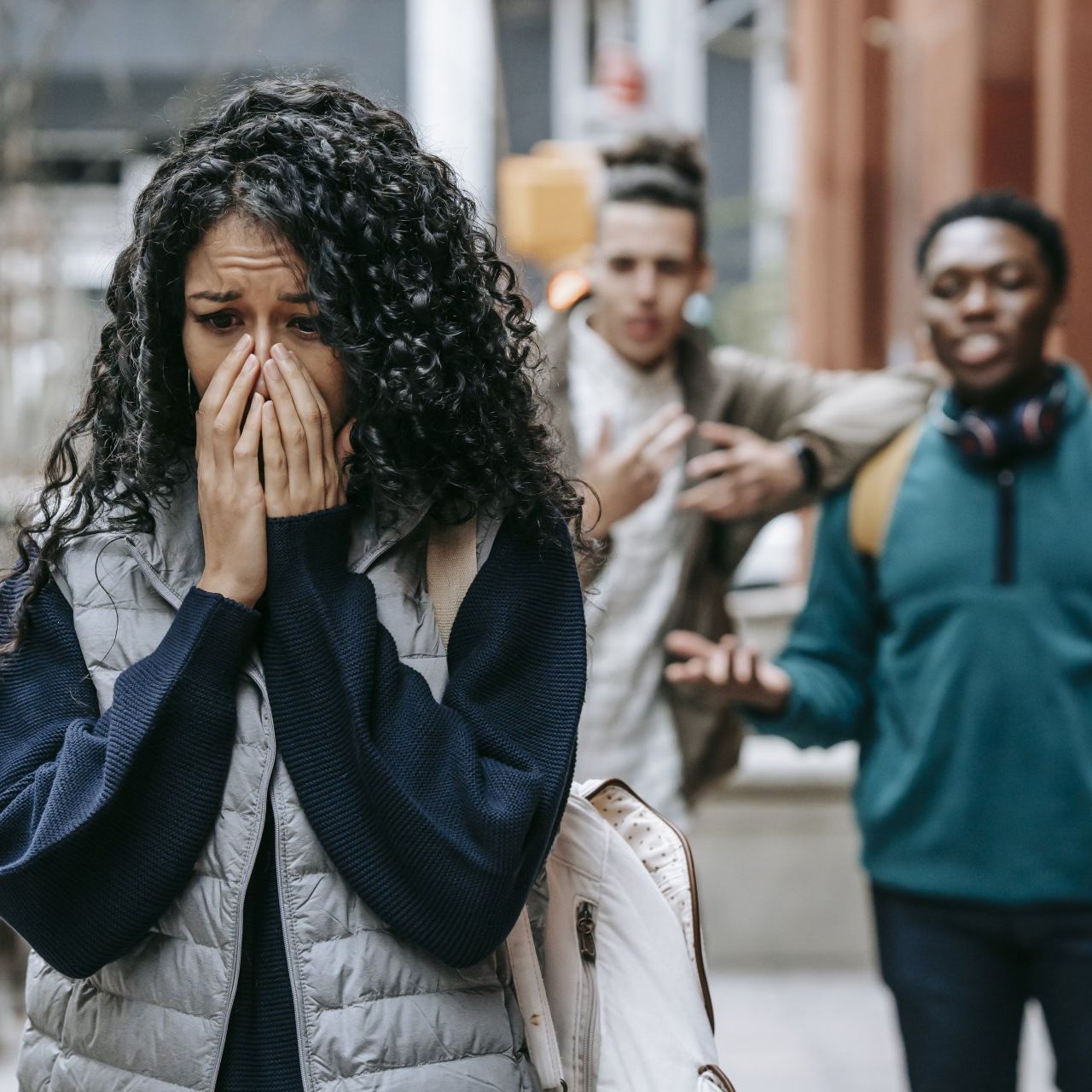 a woman is covering her face with her hands in the street feeling social anxiety