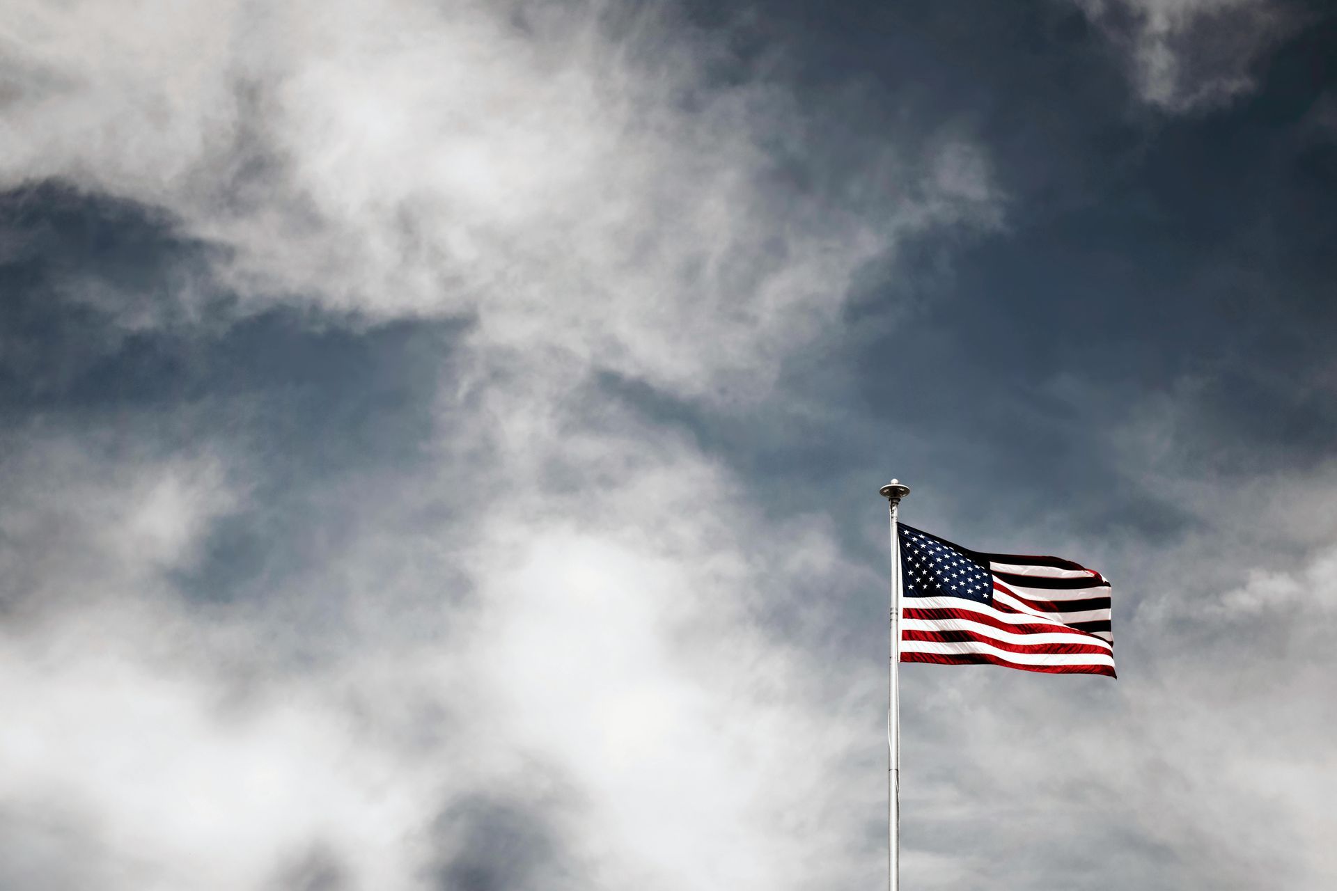 American flag waving against a cloudy sky.