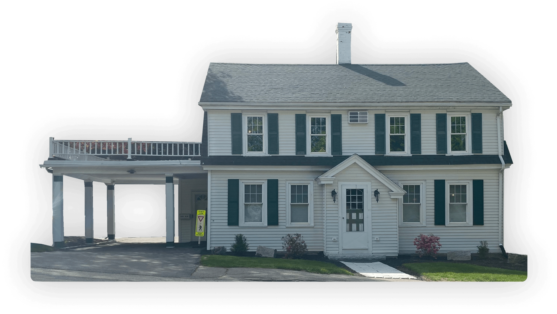 Two-story white house with green shutters and a carport with a railing on the roof.