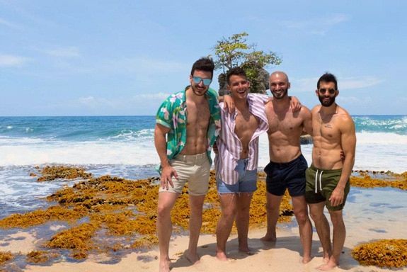 A group of men are posing for a picture on the beach.