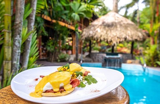 A plate of food is sitting on a table next to a pool.