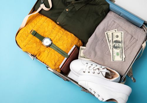 A suitcase filled with clothes , shoes , money and a watch.