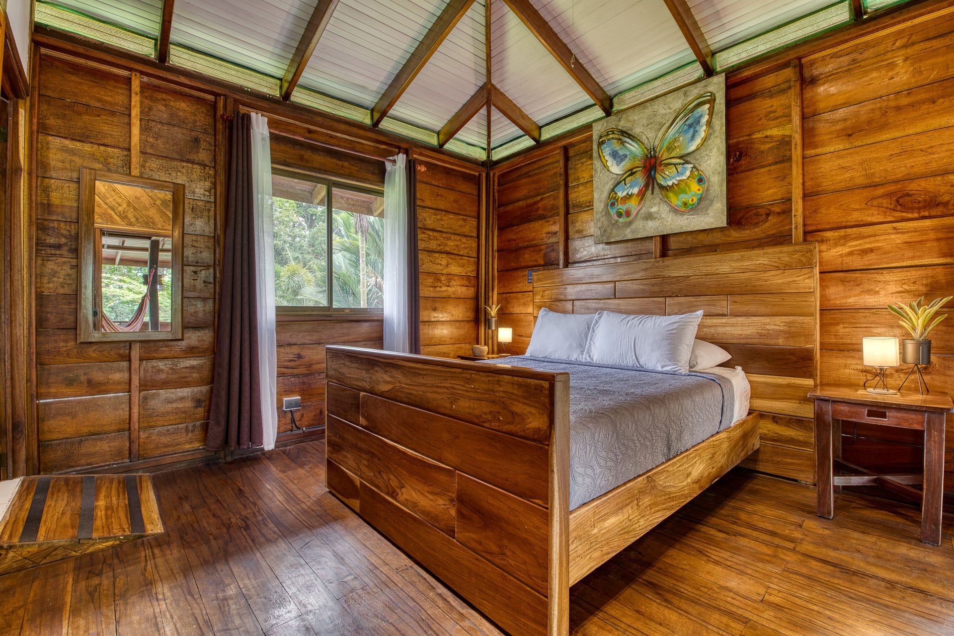 A bedroom in a wooden cabin with a bed and a mirror.