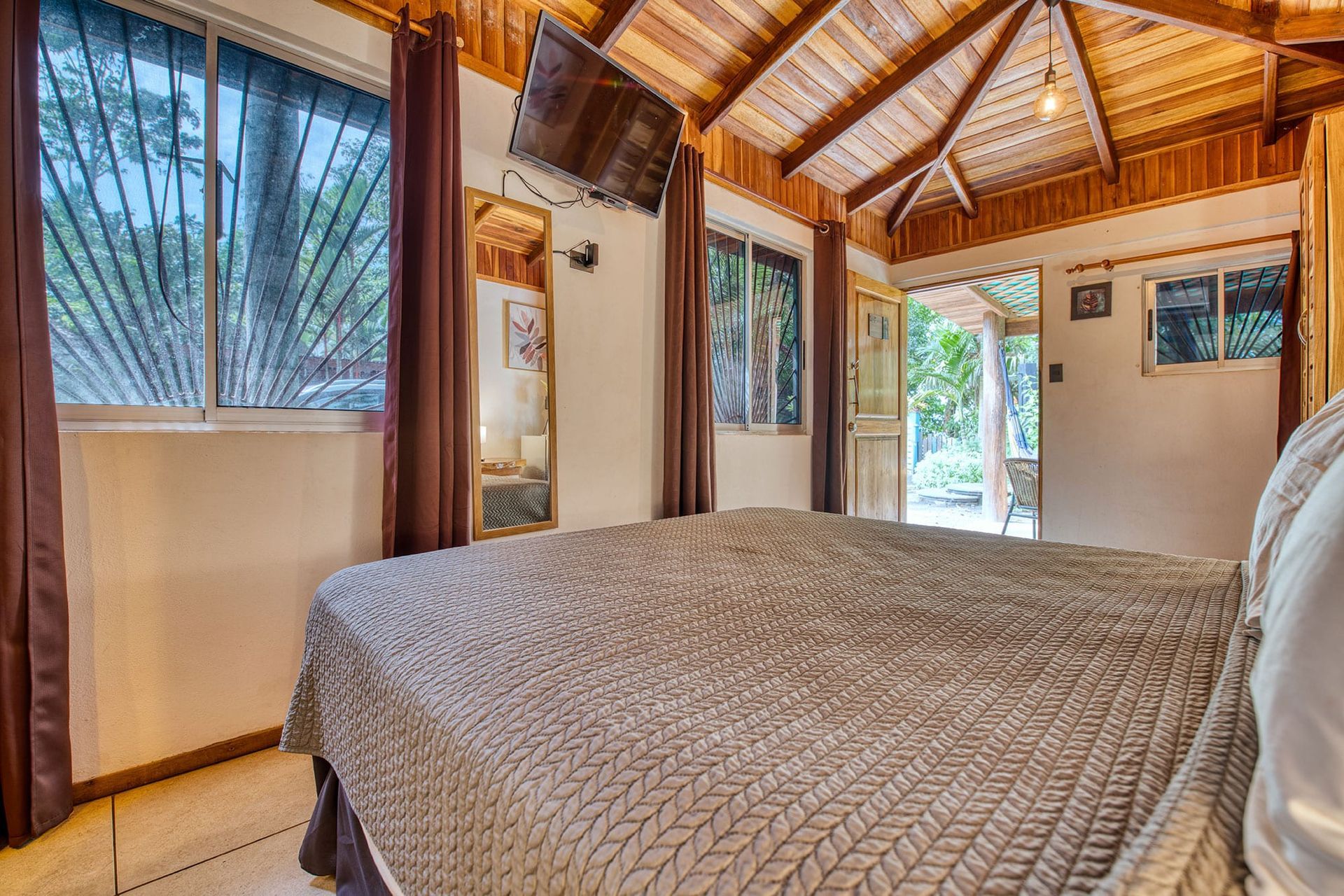 A bedroom with a large bed and a flat screen tv on the wall.