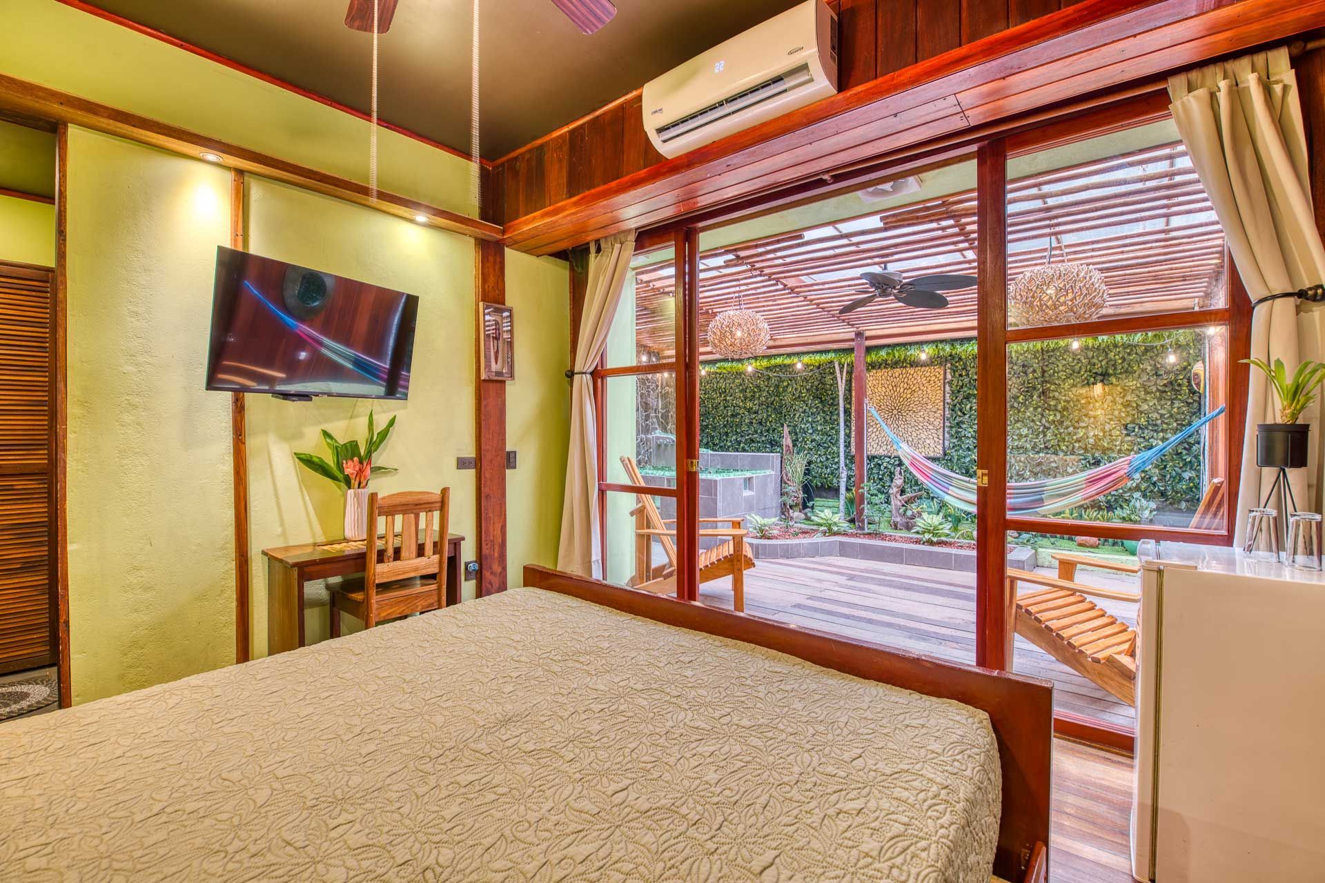 A hotel room with a bed , television , chairs and a hammock.