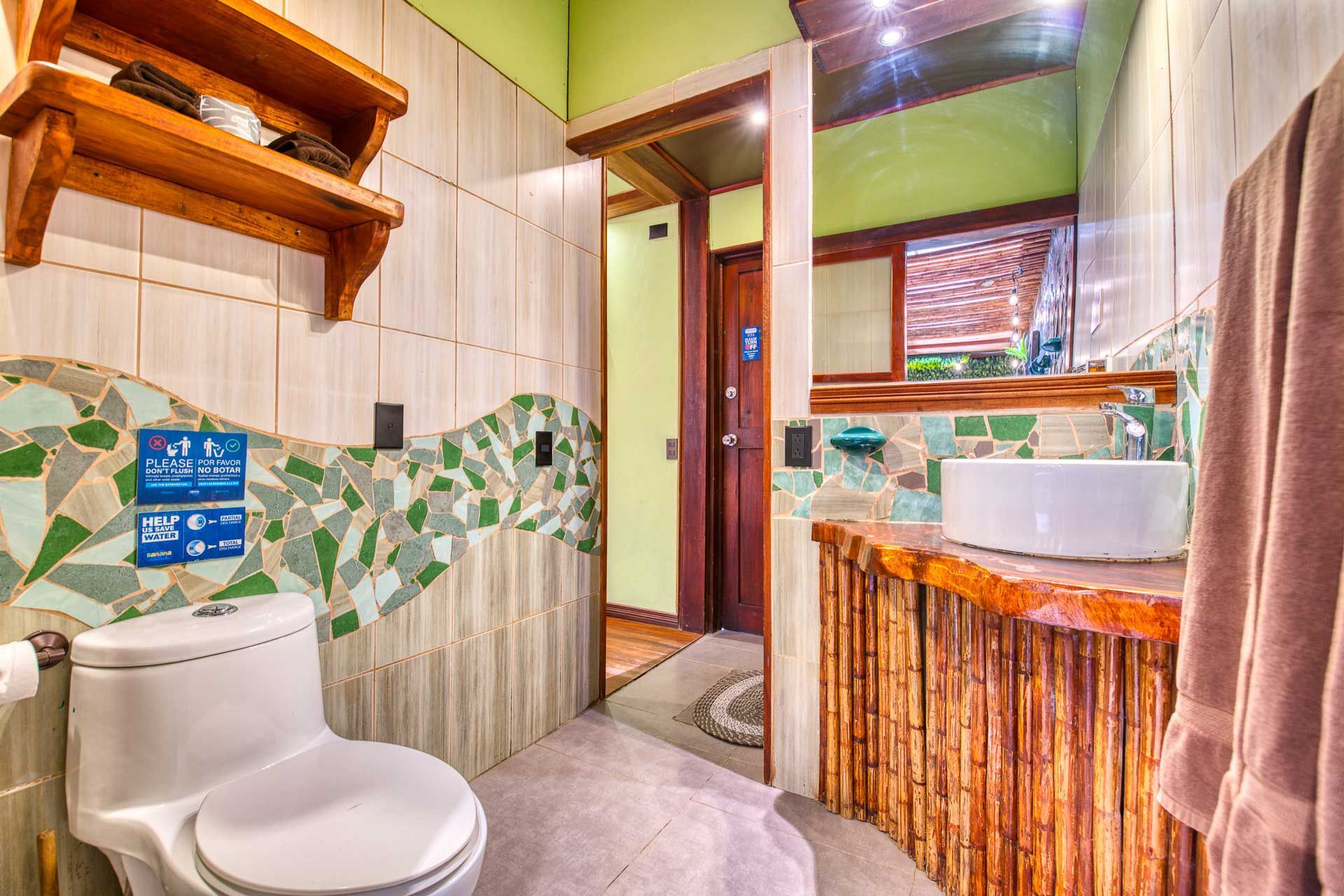 A bathroom with a toilet , sink and mirror.