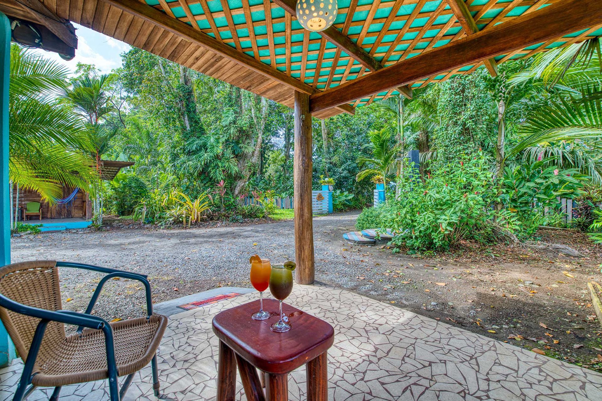 A patio with a chair and a table with two drinks on it.