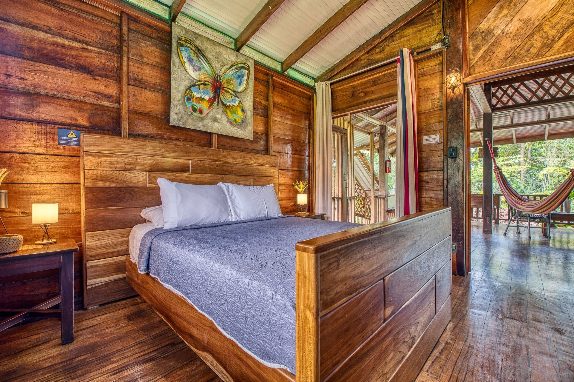 A bedroom in a wooden cabin with a bed and a hammock.