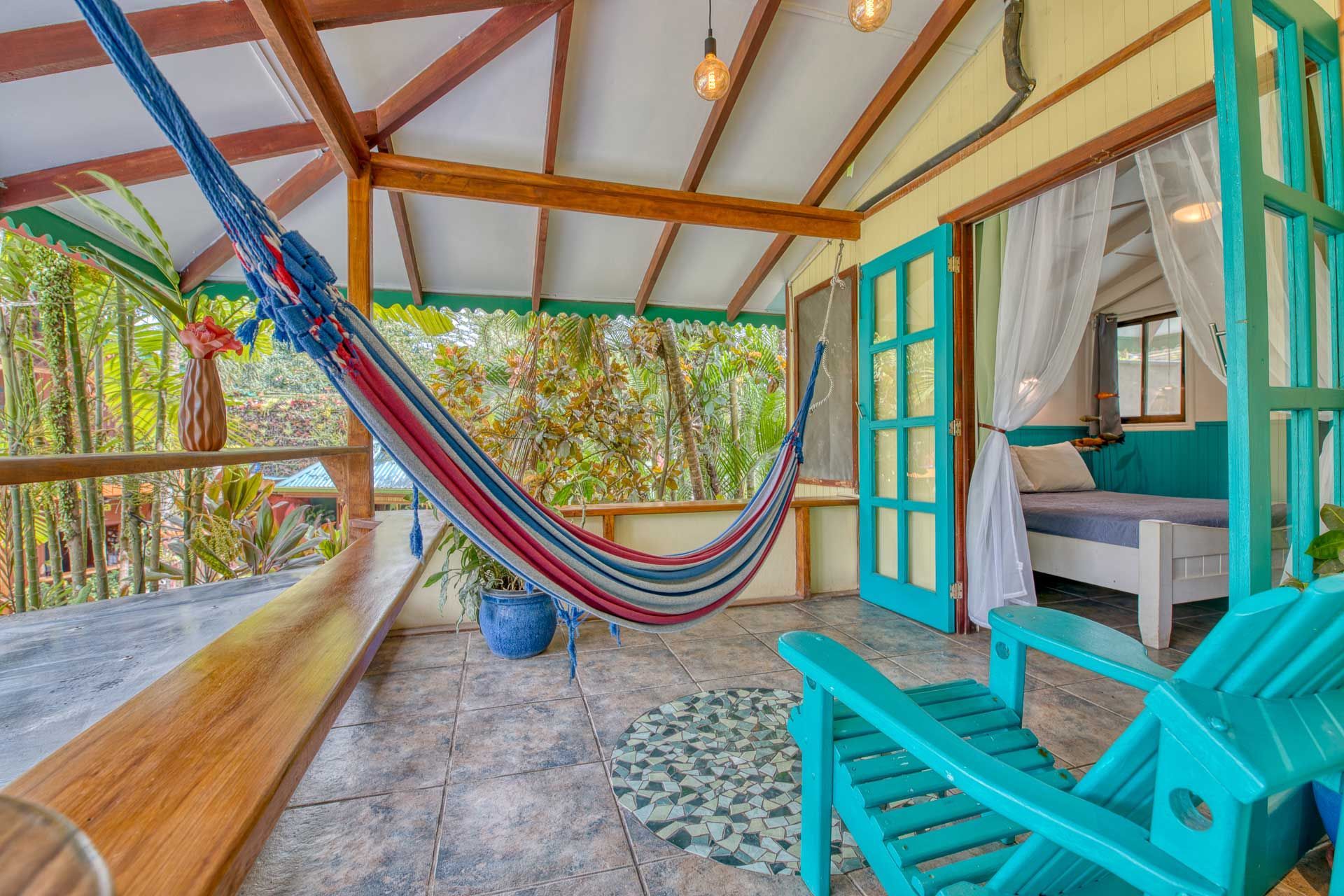 There is a hammock and a chair on the porch of a house.