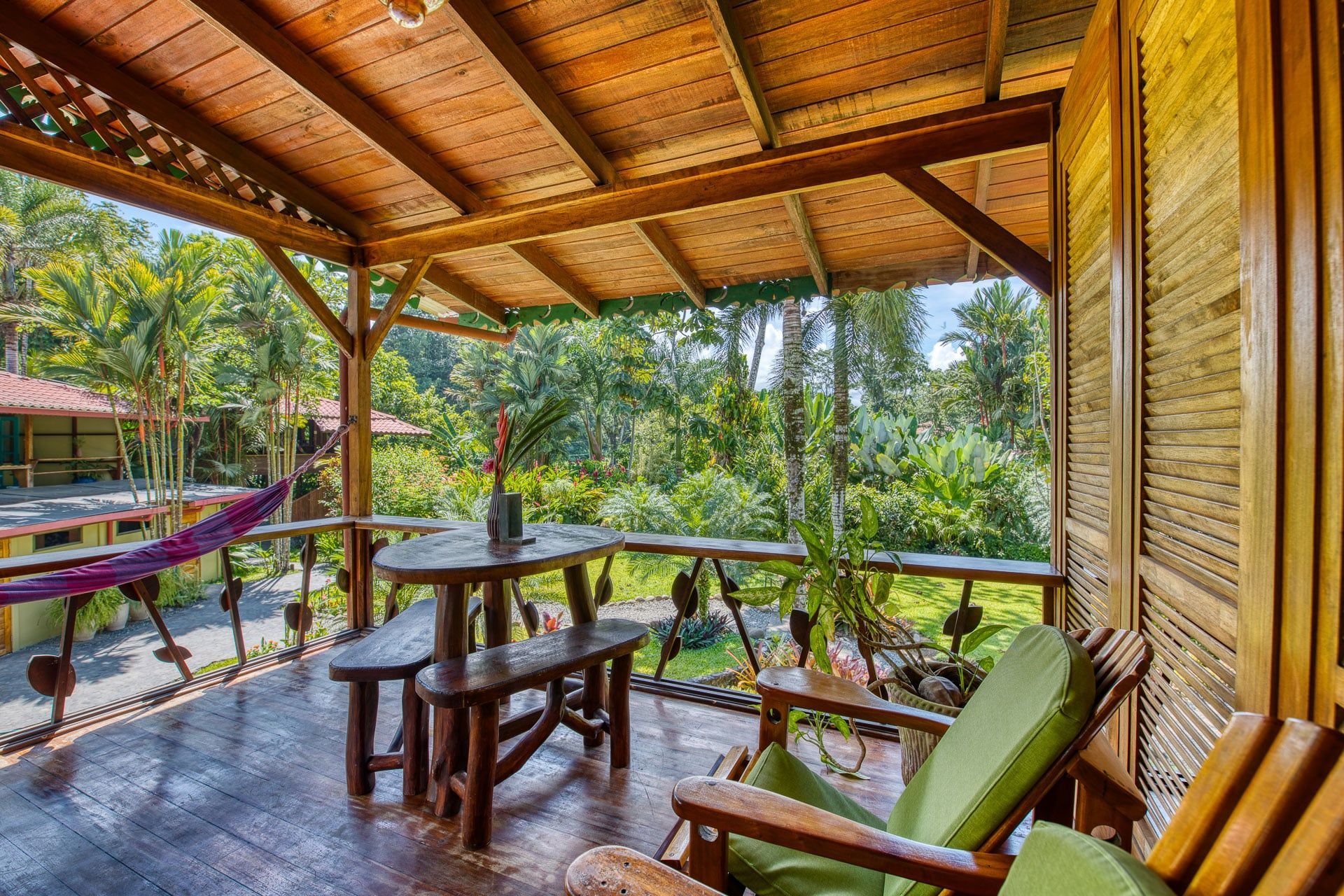 A wooden porch with a table and chairs and a hammock