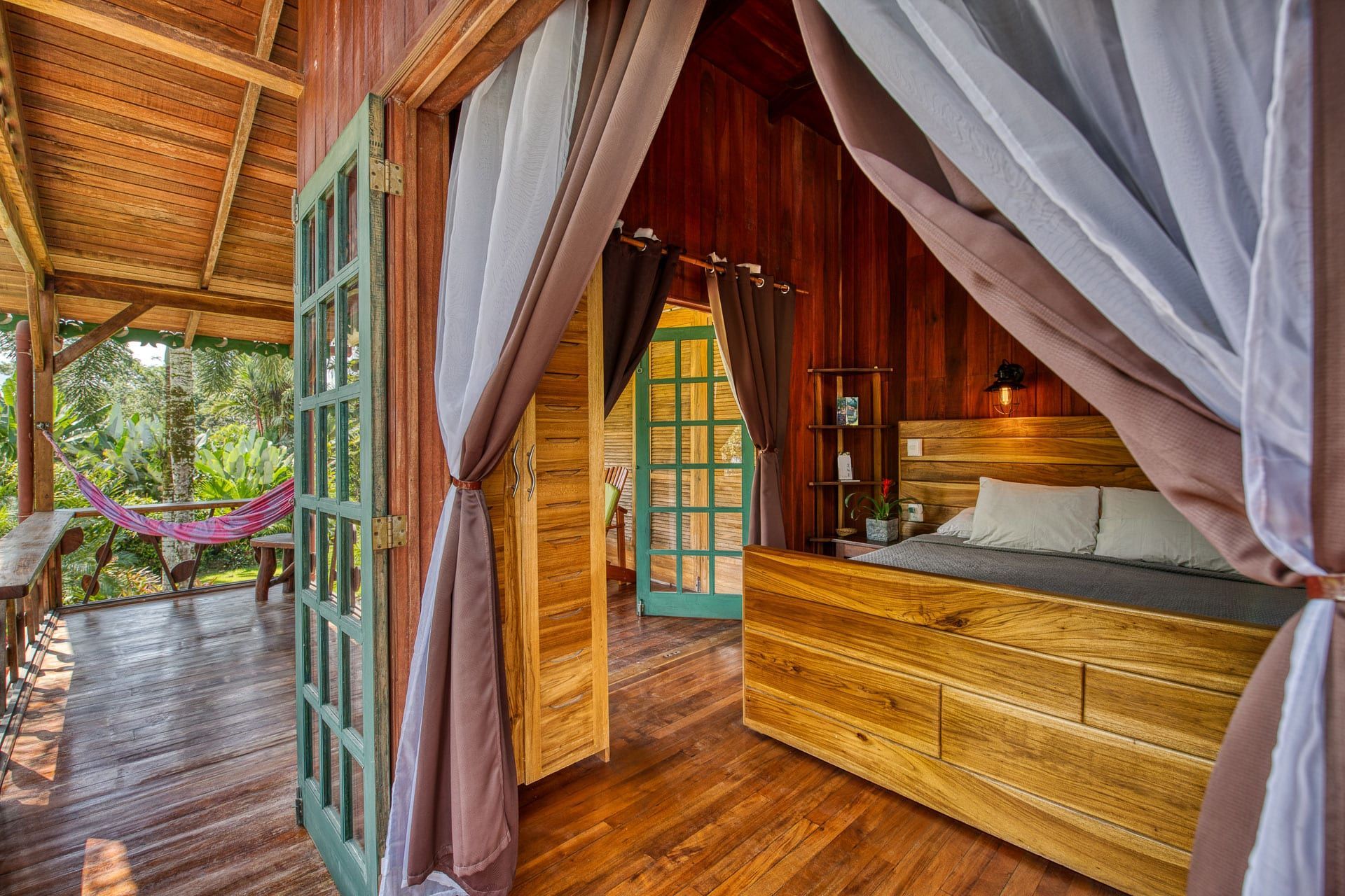 A bedroom in a wooden house with a bed and curtains.