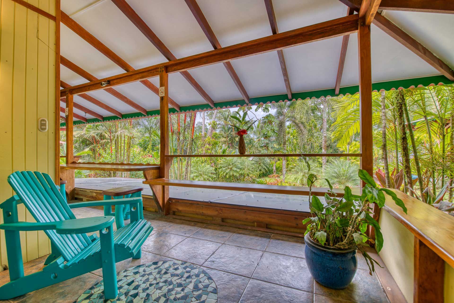 A porch with two blue chairs and a potted plant.